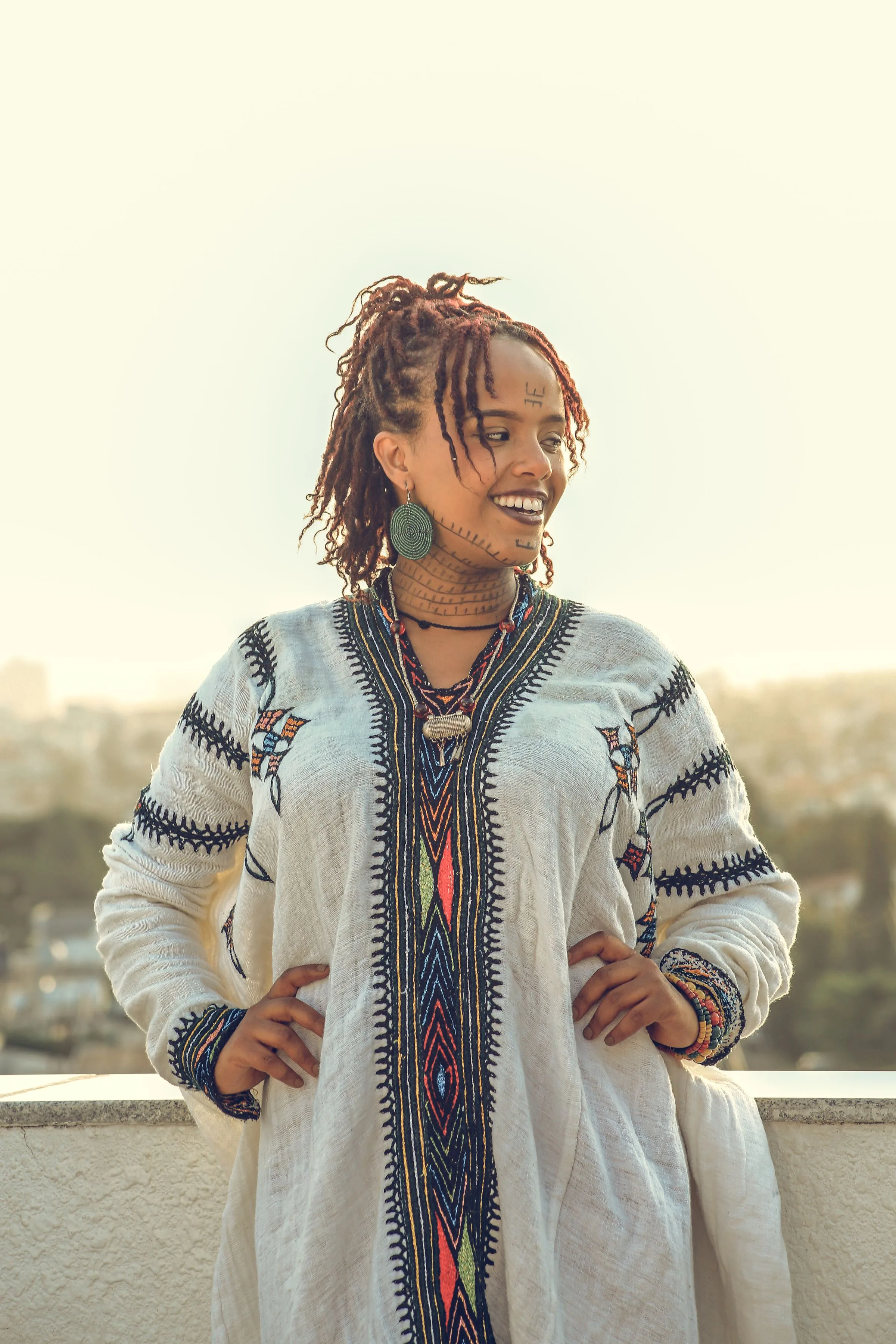 ጥልፍ ያለው የሀበሻ ቀሚስ ለብሳ አዲስ አበባ ውስጥ በህንፃ ጣሪያ ላይ ሆና ፈገግ የምትል ኢትዮጵያዊት ሴት